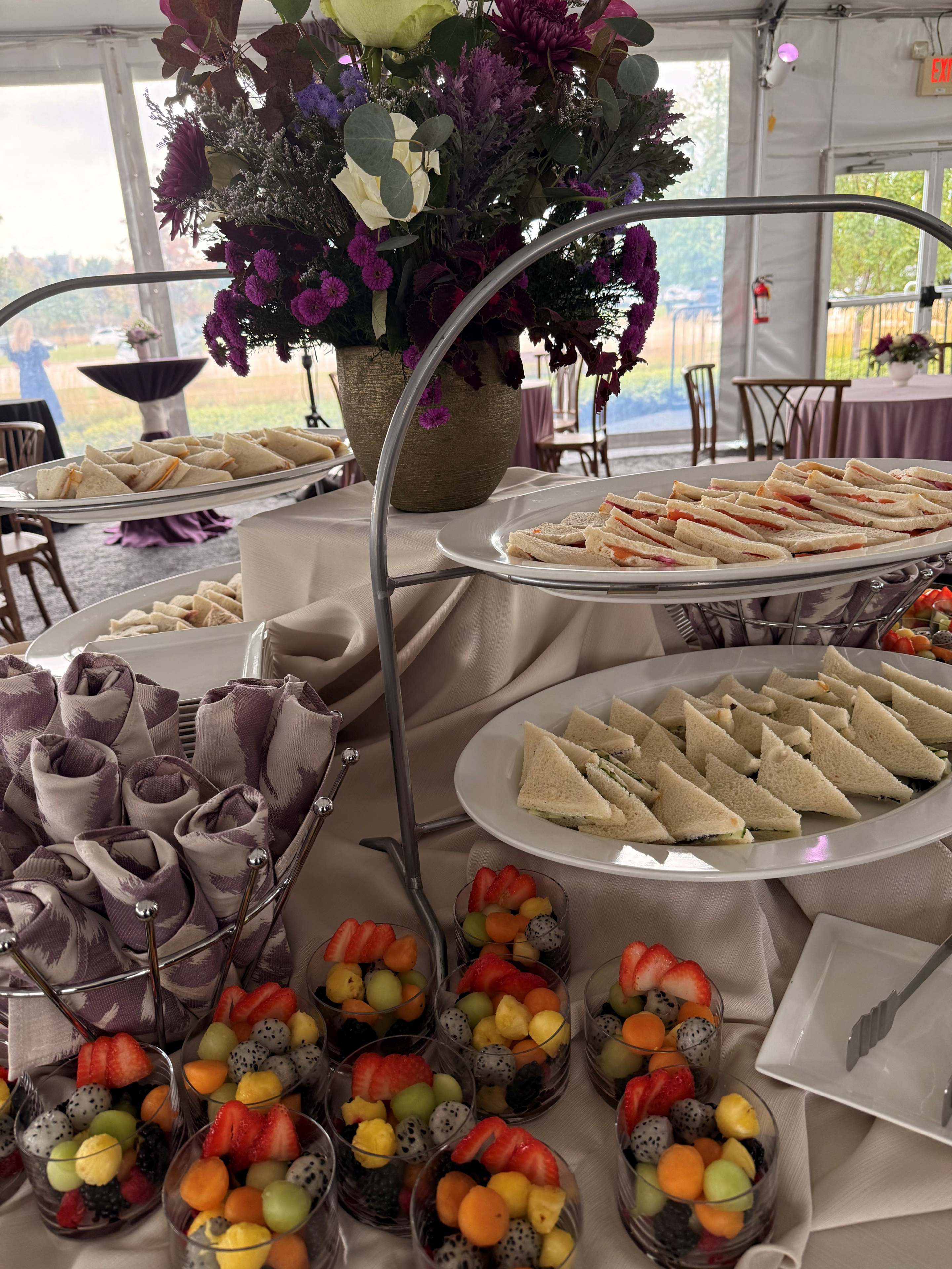 Tea sandwiches and fruit cups on display.