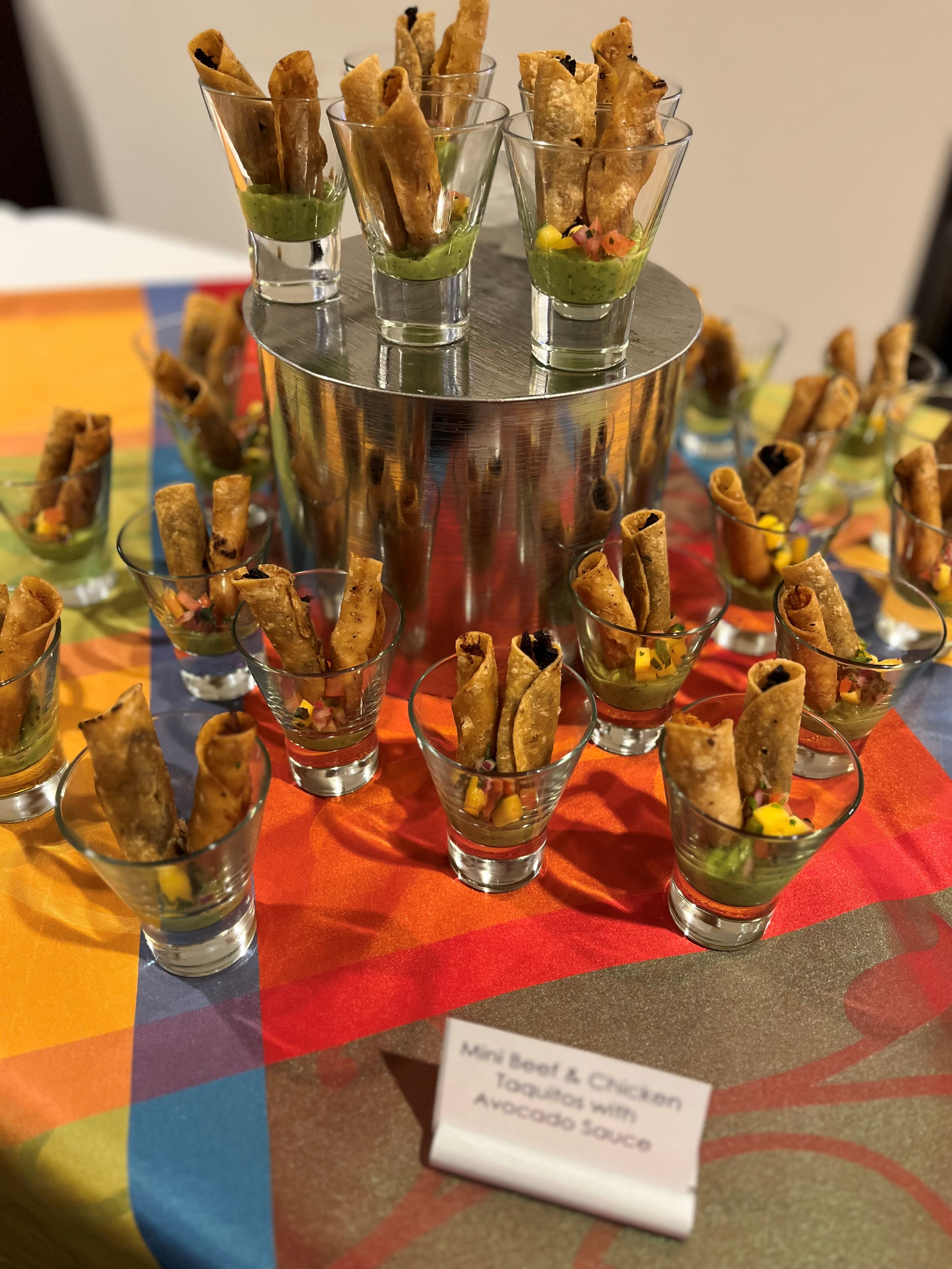 Mini taquitos with avocado sauce on display.