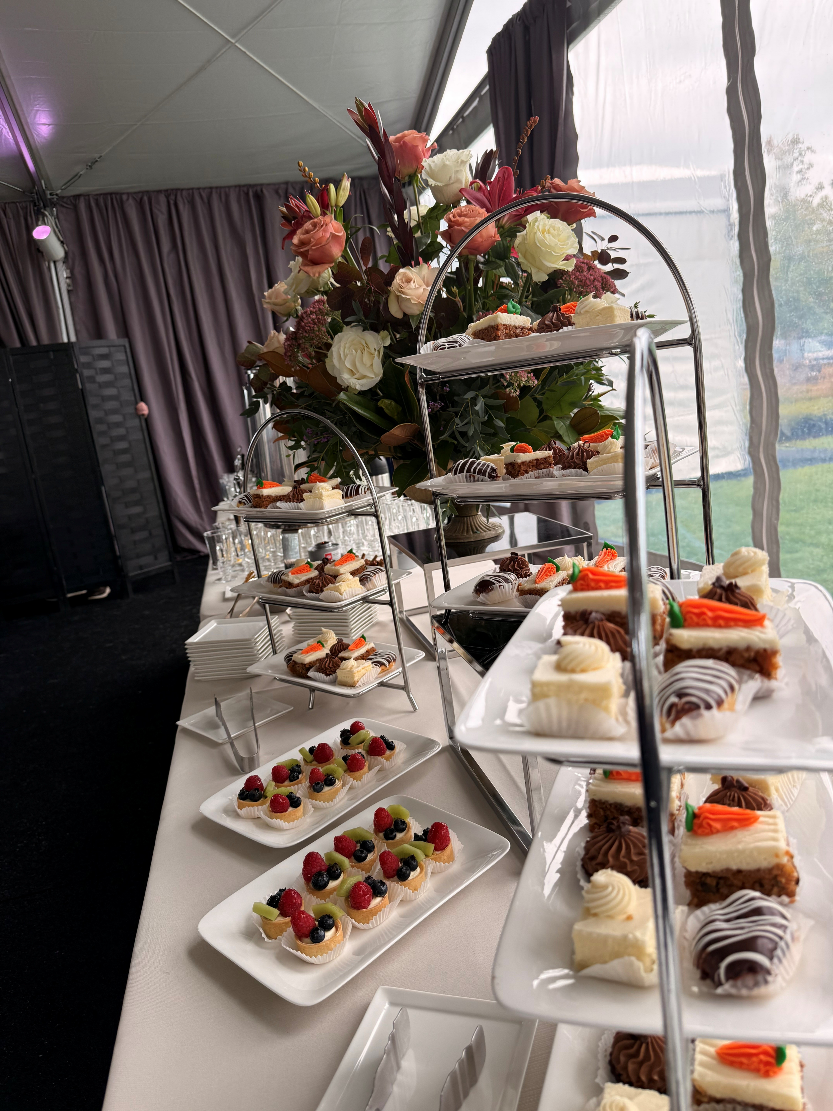 Dessert table with assorted pastries and flowers.