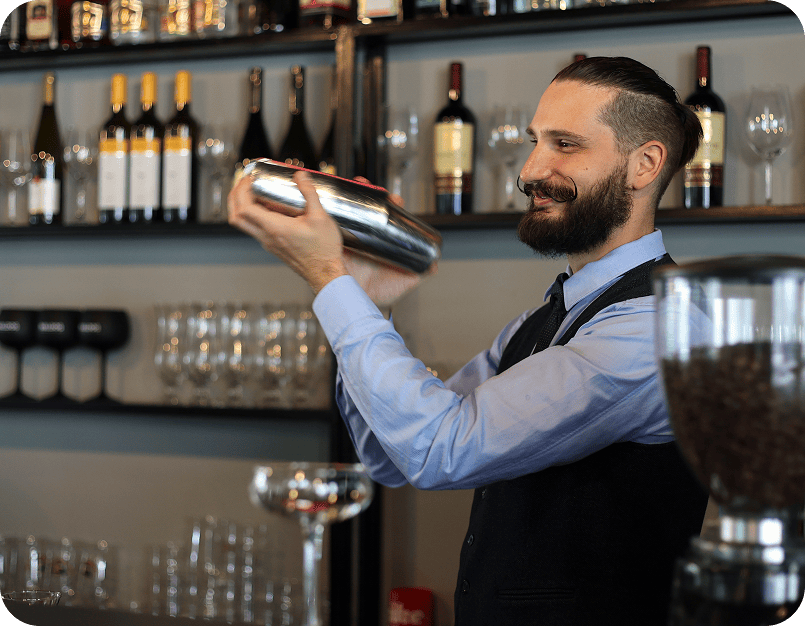 Bartender shaking cocktail shaker behind bar.